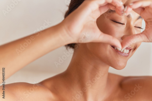 Young Woman Making Heart With Hands Around Eye, Embracing Positivity And Self-Love. Close-Up, Radiant Smile, Healthy Lifestyle, Natural Beauty.