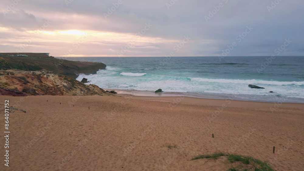 Coastal landscape lit sunset light with ocean waves gently washing sandy beach. Coastal landscape lit sunset light with ocean waves gently washing sandy beach.