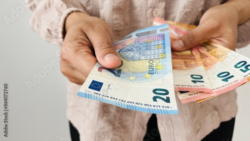 Woman holding euro money. Giving 20 euro notes and holding different bills, euro banknotes, European Union paper currency. Finance, business, investment, inflation, purchasing power and social crisis.