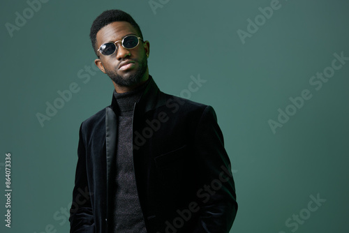 Stylish man in sunglasses and black turtleneck standing confidently against a vibrant green background