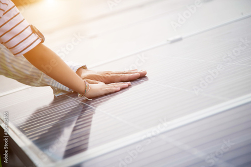 Close up of a young engineer hand is checking the operation of sun and cleanliness of photovoltaic solar panels on a sunset. Close-up of modern photovoltaic solar battery.