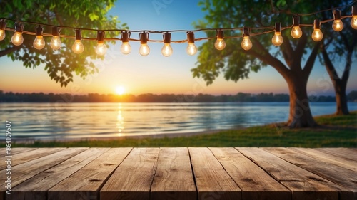 Empty Wood table top with decorative outdoor string lights hanging on trees in the revier nature  at sunset time, photo