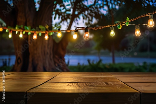 Empty Wood table top with decorative outdoor string lights hanging on trees in the revier nature  at sunset time, photo