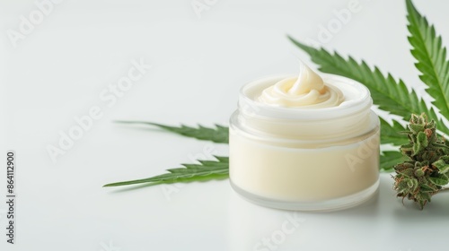 Natural cannabis cream in a jar, CBD lotion for skincare, hemp-based ointment, surrounded by cannabis leaves and buds, ample copy space on a plain background