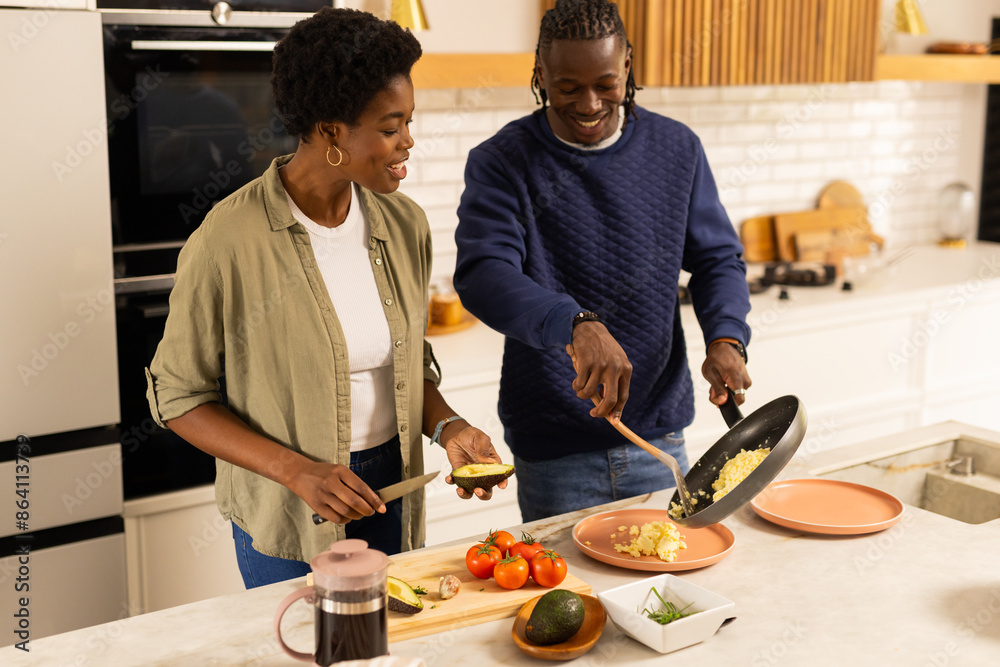 At home, Couple cooking breakfast together in modern kitchen, smiling and enjoying time At home, Couple cooking breakfast together in modern kitchen, smiling and enjoying time