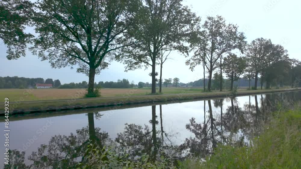 A tranquil rural landscape with a peaceful canal surrounded by trees, creating a serene and reflective scene A tranquil rural landscape with a peaceful canal surrounded by trees, creating a serene and reflective scene
