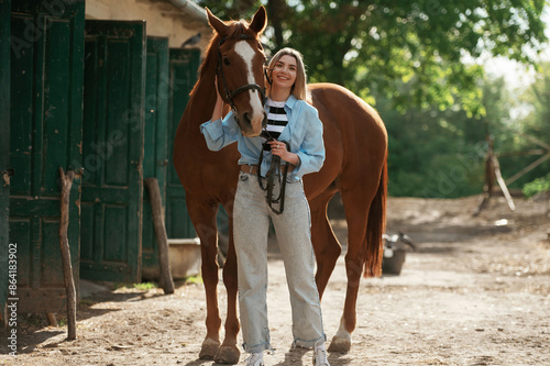 Enjoying and standing with an animal. Young beautiful woman is with a horse outdoors photo