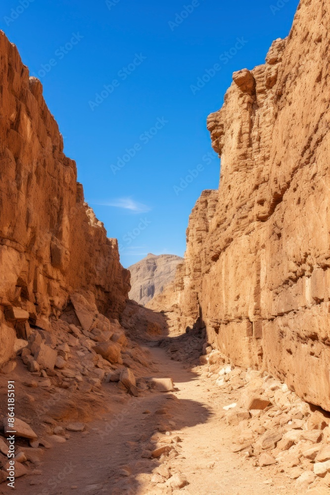 A dirt road winding between rocky cliffs in a desert landscape. A dirt road winding between rocky cliffs in a desert landscape.