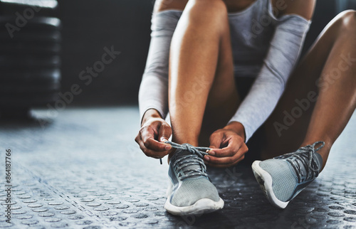 Gym, hands and person tie shoes on floor before workout for exercise, training or healthy lifestyle in morning. Fitness, wellness and athlete on ground to prepare, fasten sneakers or ready to start