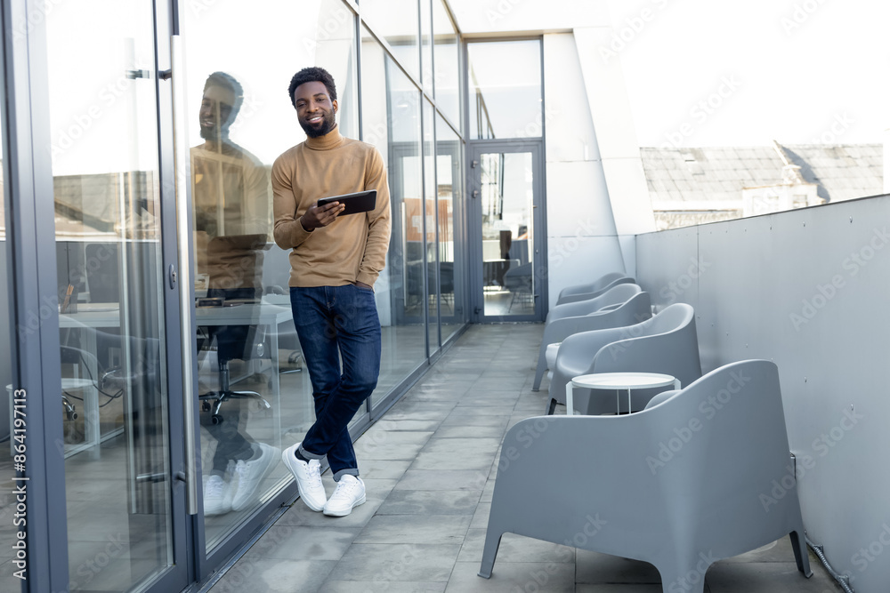 Positive african american guy with a tablet in hands standing outdoors Positive african american guy with a tablet in hands standing outdoors