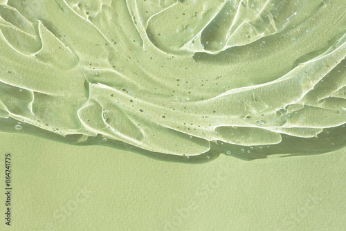 Transparent serum gel with hyaluronic acid for the face on a green background. The texture of a cosmetic product with oxygen bubbles. Wellness and beauty concept.