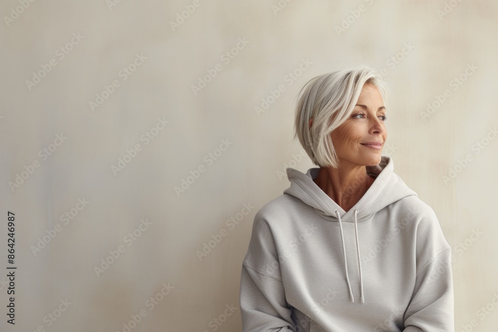 Portrait of a blissful woman in her 50s sporting a comfortable hoodie isolated on modern minimalist interior