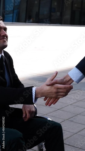businesswoman in formal suit shaking hands with disabled colleague businessman outdoor nead cool modern business centre building at sunset. Super slow motion. High speed fps 250 cameraSunny day photo