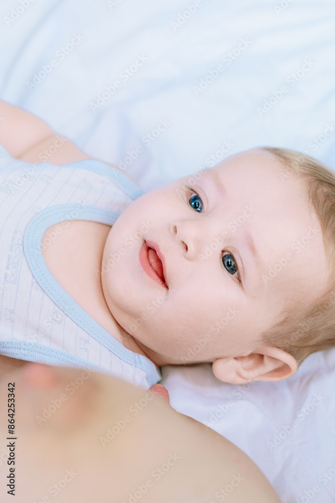 Adorable baby boy smiling while lying on a bed Adorable baby boy smiling while lying on a bed