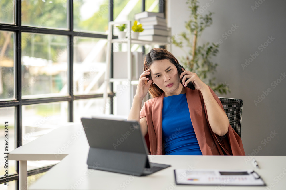 Obraz premium A woman is sitting at a desk with a laptop and a tablet
