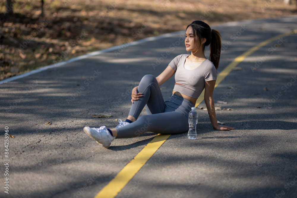 A woman is sitting on the side of a road with a bottle of water in front of her A woman is sitting on the side of a road with a bottle of water in front of her