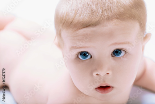 Adorable baby boy lying on stomach and looking with curiosity