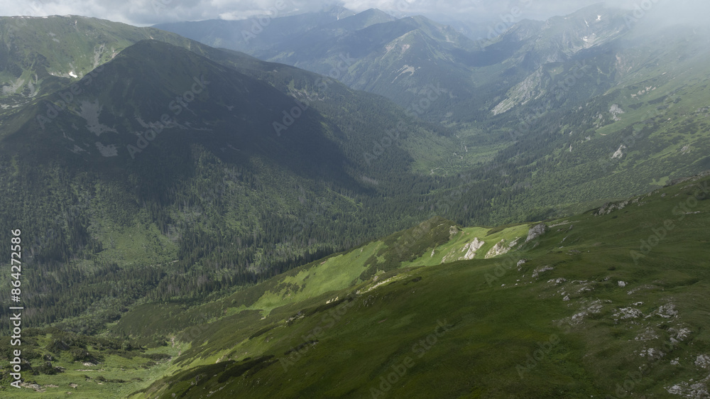 Fototapeta premium A panoramic vista of a valley nestled amongst mountains, viewed from an elevated vantage point