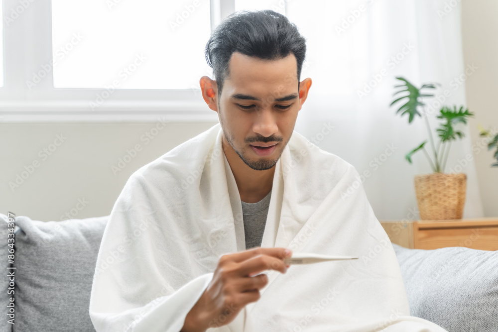Seasonal cold sickness in people concept, Sick asian man looking at thermometer during measuring his body temperature feel exhausted and headache from fever. Seasonal cold sickness in people concept, Sick asian man looking at thermometer during measuring his body temperature feel exhausted and headache from fever.