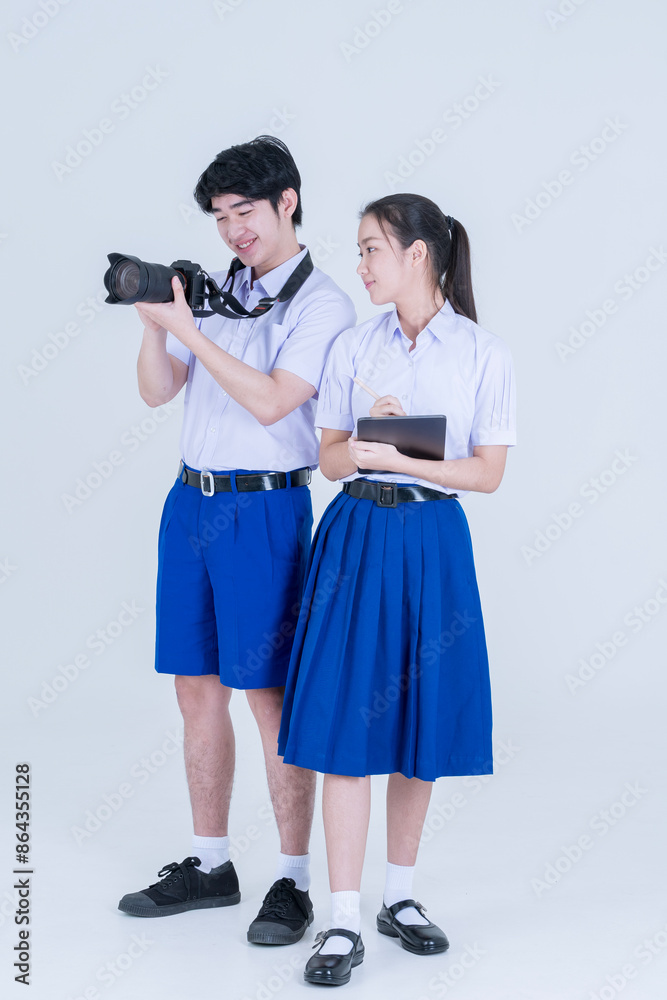 Thai high school student uniform. Boy and girl stand on white background with computer tablet and camera. Thai high school student uniform. Boy and girl stand on white background with computer tablet and camera.