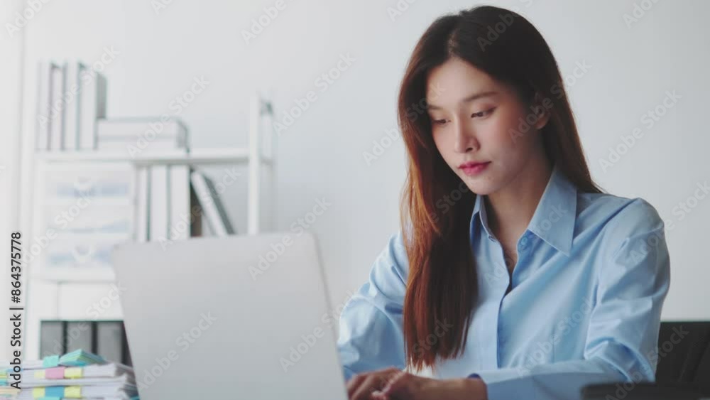 Businesswoman works on her laptop in a modern office, focusing on tasks in a clean, white decor with organized shelves Businesswoman works on her laptop in a modern office, focusing on tasks in a clean, white decor with organized shelves