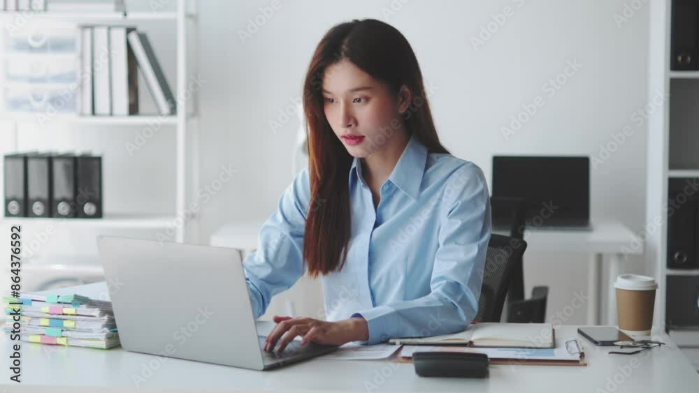 Focused businesswoman working on laptop at modern office desk, surrounded by files, coffee cup, and organized workspace, indicating productivity Focused businesswoman working on laptop at modern office desk, surrounded by files, coffee cup, and organized workspace, indicating productivity