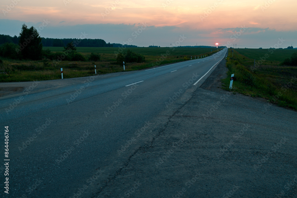 Fototapeta premium A long road with a sunset in the background