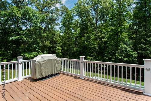 Obraz na płótnie Summer Outdoor Deck with White Railings and Lush Green Forest View, Covered Grill w salonie