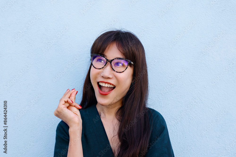 Happy Asian Woman Smiling And Having an Great Idea. She Wears Glasses Over Light Blue Background Happy Asian Woman Smiling And Having an Great Idea. She Wears Glasses Over Light Blue Background