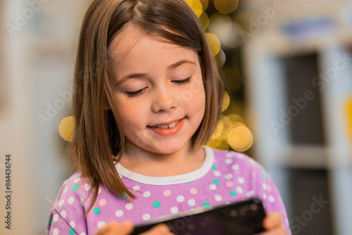 Child looks at smartphone at Christmas time at home. Children and technology. photo