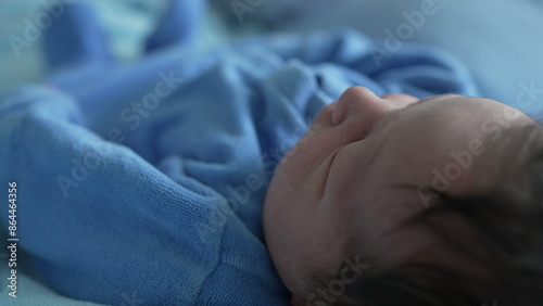 Close-up view of a newborn baby resting peacefully, highlighting the fine details of the baby's hair and skin, emphasizing the tranquility and innocence of early life, wrapped in a blue blanket