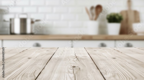 A light-colored wooden table top with blurred kitchen counter background, vacant room and kitchenware in the backdrop with copy space for text photo
