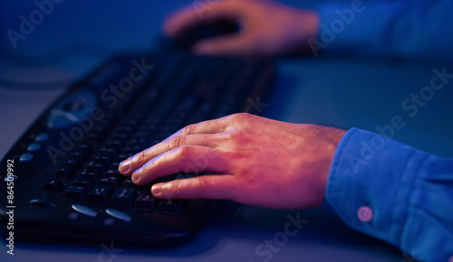 Fotografija A close-up photograph captures a hand typing on a black keyboard, with the fingers hovering over the keys