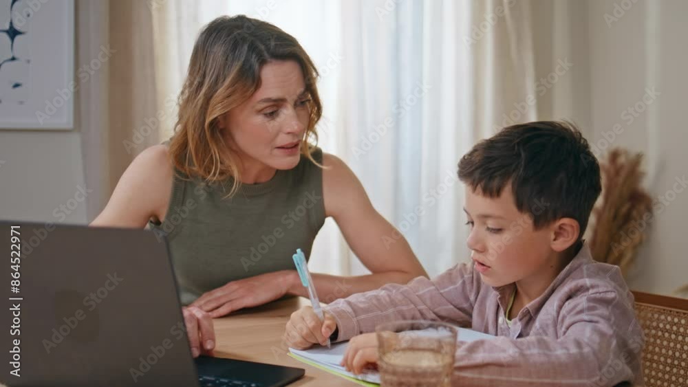 Closeup mom teaching son doing homework together in living room. Woman and child
