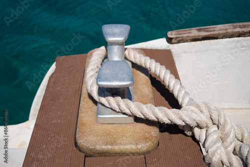 Loop of white spiral rope around steel anchor on boat. Mooring rope used for securing the ship to the harbour. Elements of ship and boat equipment