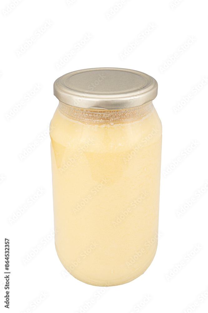 Ghee or clarified butter in jar isolated on white background. Clarified butter contains healthy fat and is a commonly used cooking ingredient in many Turkish cuisines. Ghee or clarified butter in jar isolated on white background. Clarified butter contains healthy fat and is a commonly used cooking ingredient in many Turkish cuisines.