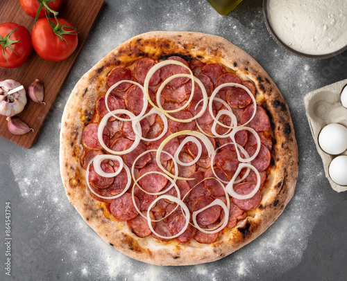 Calabrese sausage style pizza over stone background with ingredients