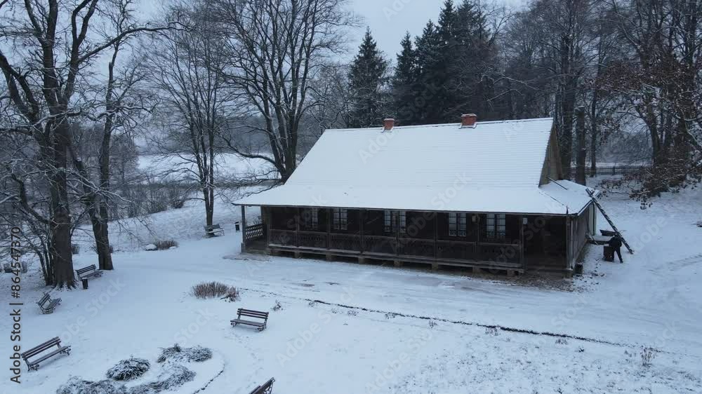 Cozy snow covered wooden house among snowy forest during snowfall Cozy snow covered wooden house among snowy forest during snowfall