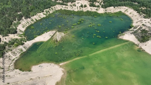 Aerial drone view of flooded sand pit. An artificial lake after a flooded sand pit. Forest submerged in a lake. Sunken sandpit with crystal clear water in Klucze, Poland.