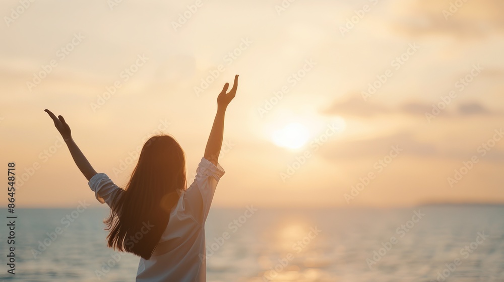Woman enjoying the serene sunset by the sea, raising hands in a gesture of freedom and tranquility. Perfect for themes of relaxation and nature. Woman enjoying the serene sunset by the sea, raising hands in a gesture of freedom and tranquility. Perfect for themes of relaxation and nature.