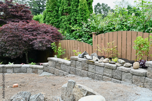Yard and garden project in building progress, brick and rock walls bordering terraced flowerbeds and pathways.