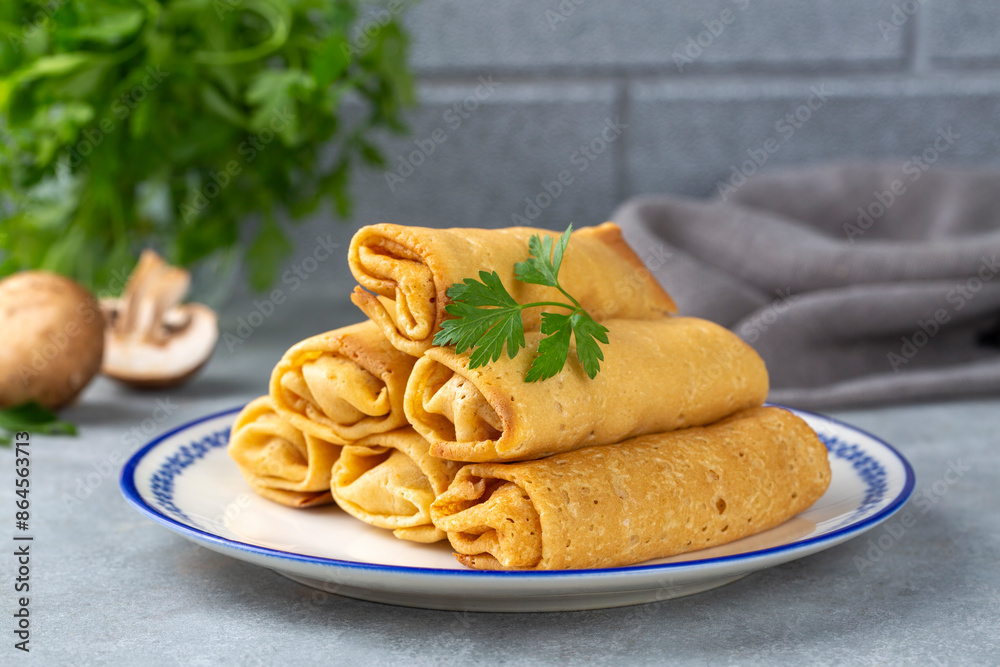 Pancakes or thin crepes stuffed with chicken and mushrooms on a plate