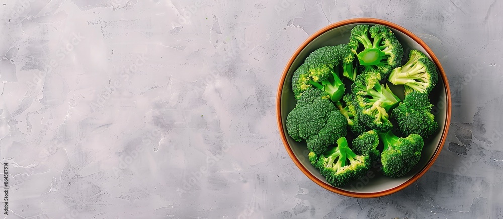 Obraz premium Top-down view of a bowl of fresh broccoli on a light grey table with ample space for text alongside the copy space image.