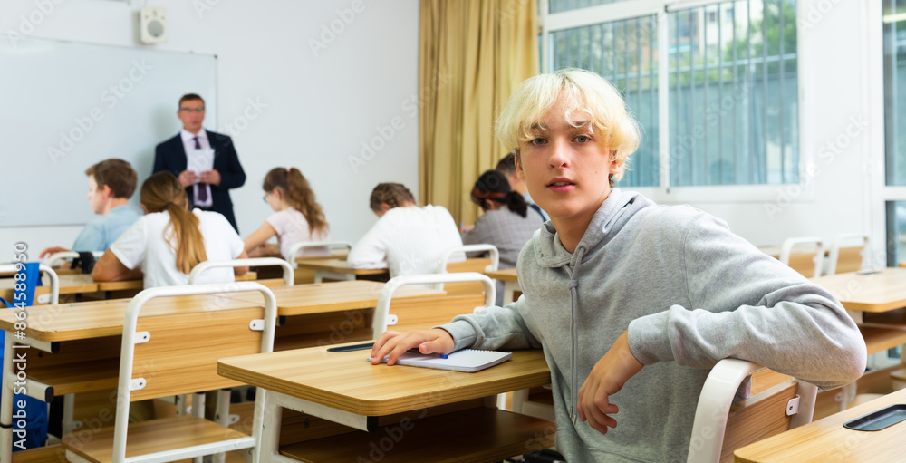 Fototapeta premium Young teenager is sitting at the desk in the classroom