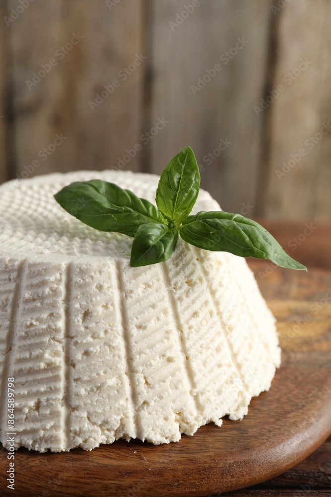 Tasty ricotta (cream cheese) and basil on wooden table, closeup