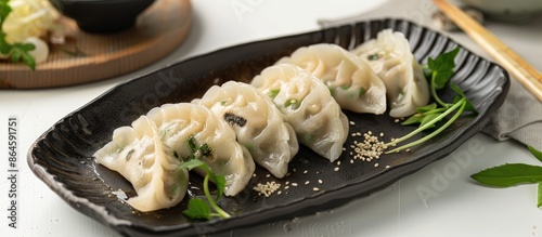 Japanese dumplings displayed on a black plate against a white backdrop, garnished with soybean flour and green tea, featuring a mugwort-infused rice dumpling. Copy space image.