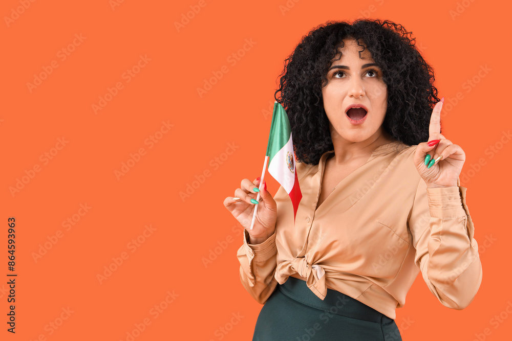 Beautiful woman with Mexican flag pointing at something on orange background Beautiful woman with Mexican flag pointing at something on orange background