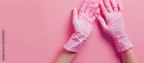 Adan's creation features two hands in latex gloves rubbing fingertips on a pink background with copy space image. photo