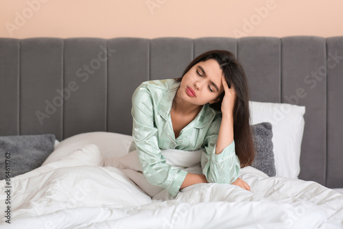 Morning of young beautiful sleepy woman sitting in bedroom at home