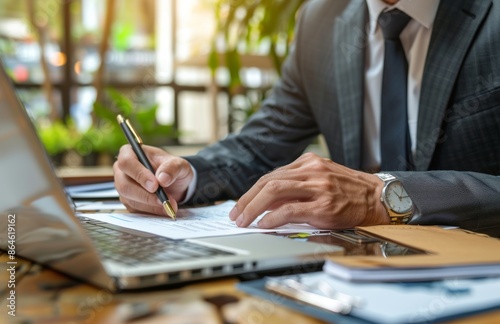 Businessman Working on Laptop With Financial Documents in Office